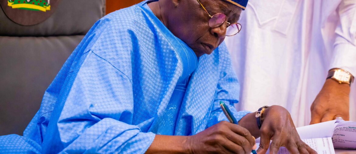 President Bola Ahmed Tinubu sitting at a microphone